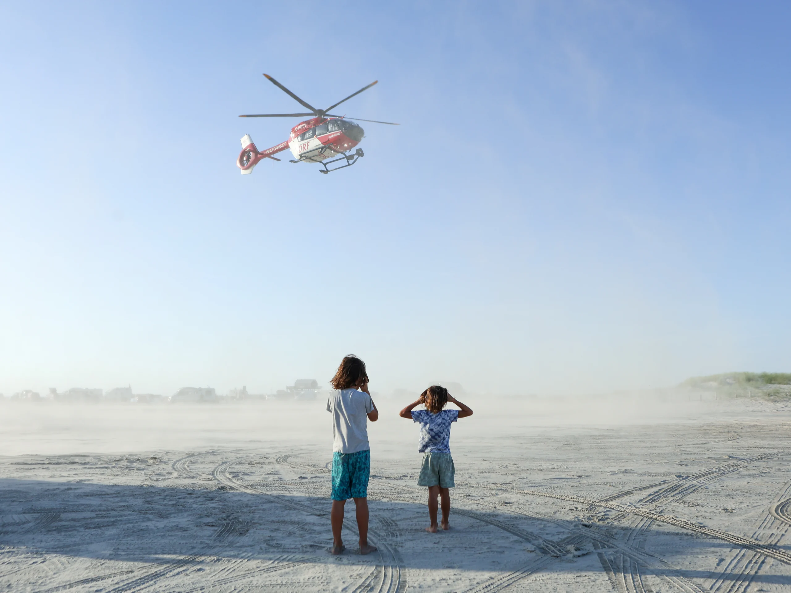 Zwei Kinder am Strand beobachten einen Rettungshubschrauber – Fotografie Anastasia Hrytsenko